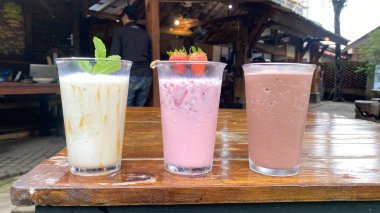 Tahta bir masada çilekli ve yaban mersinli smoothie.