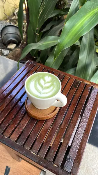 bir fincan yeşil çay ve ahşap masada kahve.