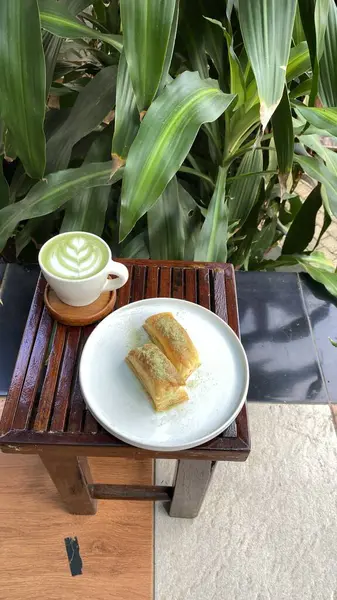 Bir fincan yeşil çay ve masada beyaz bir pasta.