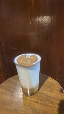 Tahta arka planda dondurmalı bir fincan kahve.