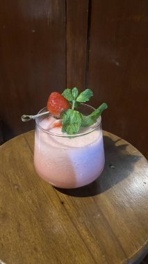 Tahta üzerinde nane yaprakları olan çilekli smoothie.