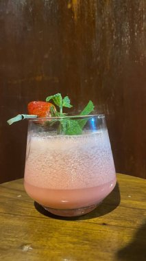 Tahta arka planda bir kamışla bir bardak taze meyve suyu.