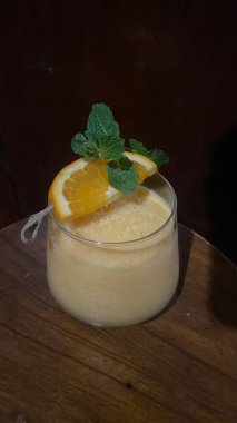 Siyah arka planda bir kaşık ve limonlu bir bardak kokteyl.