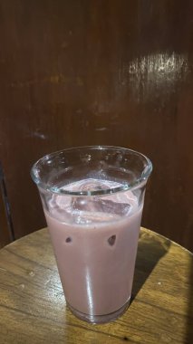 Tahta bir masanın üzerinde bir bardak sütle bir fincan kahvenin yakın çekimi.