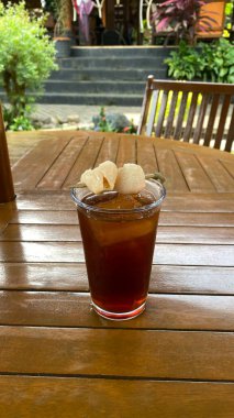 a glass of ice tea on a wooden table.