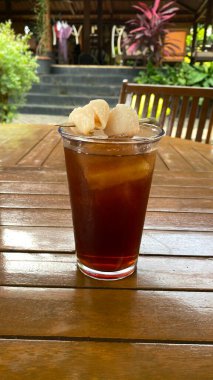 Tahta masanın üzerinde buz küpleri olan bir bardak buzlu çay