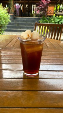 Cam bardakta buzlu çay ve ahşap masada nane yaprakları.