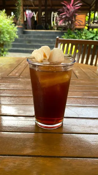 Tahta masanın üzerinde buz küpleri olan bir bardak buzlu çay