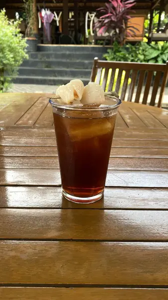 Cam bardakta buzlu çay ve ahşap masada nane yaprakları.