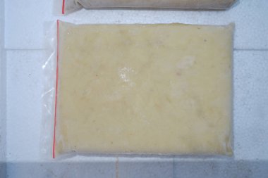 Beyaz bir yüzey üzerinde beyaz bir tabakta bıçaklı bir peynir parçası.