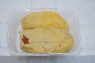 Beyaz bir arka planda plastik bir kapta çiğ bir tavuğun yakın plan çekimi.