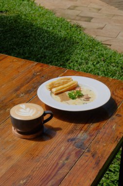 Bir fincan kahve, bir parça kek ve tahta masada bir kaşık.