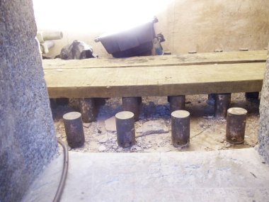 Kırsal ahşap bir tahta, bodrum ya da mahzen içinde silindirik metal bacaklar tarafından desteklenir. Yapı, kaba beton ve ahşap bir iskelet sergiliyor..