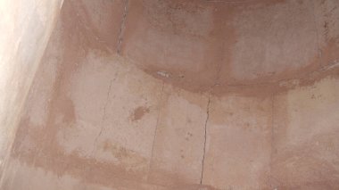 Çatlak ve yıpranmış dokusu olan yıpranmış bir yüzeyi olan kerpiç duvarının yakın görüntüsü. Görüntü, duvarın kırsal cazibesini ve toprak tonlarını vurguluyor. Yaşını ve yapısında kullanılan doğal maddeleri vurguluyor..