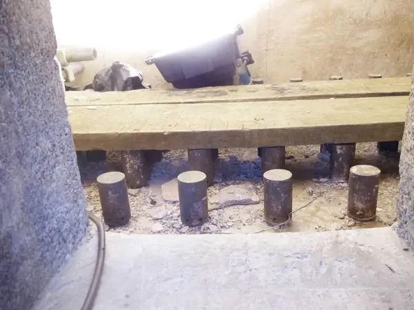 Kırsal ahşap bir tahta, bodrum ya da mahzen içinde silindirik metal bacaklar tarafından desteklenir. Yapı, kaba beton ve ahşap bir iskelet sergiliyor..