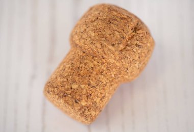 Mantar tıpası yakın planda gösterilir. Durucu kahverengi ve pürüzlü bir dokusu var. Durdurucu beyaz bir yüzeye yerleştiriliyor, bu da ona renk ve dokuda bir kontrastlama sağlıyor.