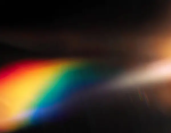 Bulanık renkli sıcak gökkuşağı ışığı toz dokusuyla siyah arkaplanda sızar