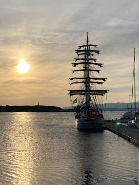 Üç direkli yelkenli gemi Oban limanında gün batımının arka ışığında