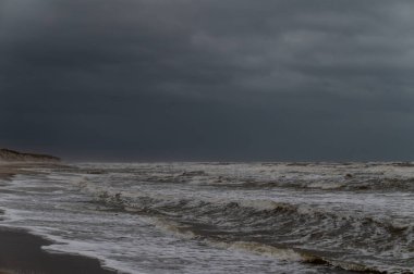 Soğuk ve rüzgarlı bir günde ıssız bir plaj. Fırtınalı deniz ve bulutlu gökyüzü dramatik ve barışçıl bir atmosfer yaratır. Vahşi okyanus tarafından doğa ile bir arkadaşlık ve bağlantı anı. Seyahat, yalnızlık ve birliktelik temaları için mükemmel..