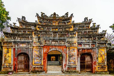 Vietnam 'daki Hue İmparatorluk Şehri' nin karmaşık, süslü kapısı. Canlı renklerle detaylı mimari ve geleneksel Vietnam tasarımı. İlerideki saraya bir göz atalım..