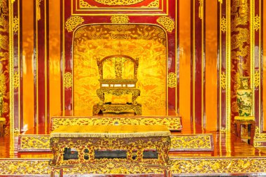 Geleneksel bir Vietnam sarayında tahta taht ve masa süsleyin. Ayrıntılı oymalar ve canlı renkler kraliyet dekorunu vurguluyor.