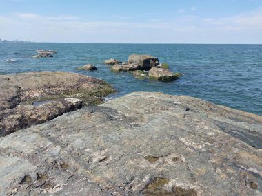 Arkasında kayalar ve şehir olan deniz kıyısı..