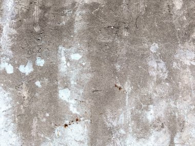 Kaba ve pürüzlü bir beton duvara yakın çekim, düz olmayan bir yüzey, küçük taşlar ve yıpranmış bir görünüm.. 