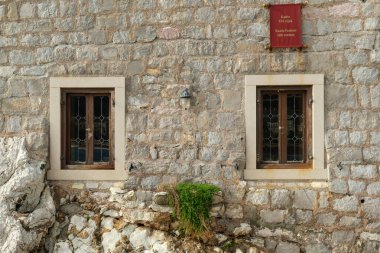 İçinde dekoratif camlı iki ahşap pencere olan tarihi bir taş duvar, eski bir fener.