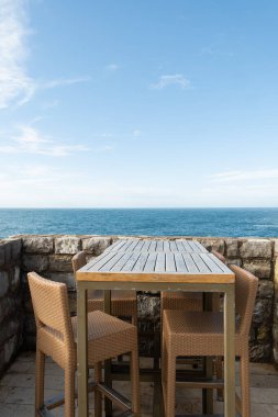Paslı bir araba çuval ve birbirine dolanmış balık ağlarıyla dolu liman kenarında oturuyor, kıyı kasabası ve arka planda dağlar var.. 