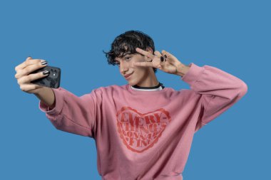 Sosyal medya için içerik yaratan, selfie çeken ve barış işaretini parmaklarıyla yapan modacı.