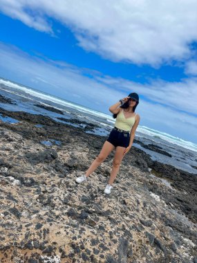 Genç esmer kız denizde şapkasını düzeltiyor.