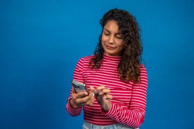 Gülümseyen kadın cep telefonu uygulaması kullanıyor, mesaj yazıyor veya internette geziniyor