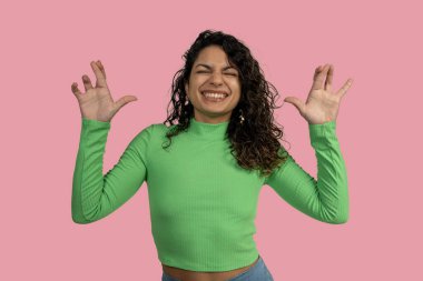 Neşeli genç bir kadın elleriyle komik pençeler yapıyor, gülümsüyor, neşe ve neşe ifade ediyor.