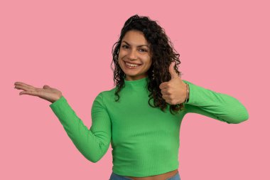 Gülümseyen kadın başparmağını kaldırıyor ve avuç içi açık bir şey sunuyor.