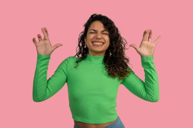 Neşeli genç bir kadın elleriyle komik pençeler yapıyor, gülümsüyor, neşe ve neşe ifade ediyor.