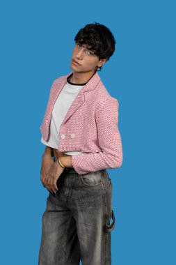 Pembe ceketli şık bir genç adam ve mavi arka planda duran gökkuşağı bileziği.