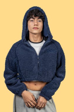 Modaya uygun genç adam mavi kürklü kırpık kapüşonlu kapüşonlu ve gri eşofmanlı ciddi bir ifadeyle