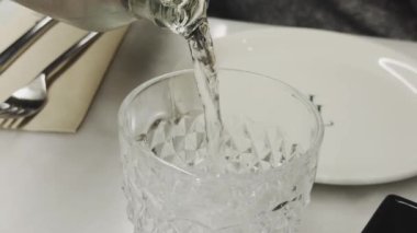 Cam bir şişeden kristal bardağa dökülen berrak su canlandırıcı bir görüntü oluşturur.