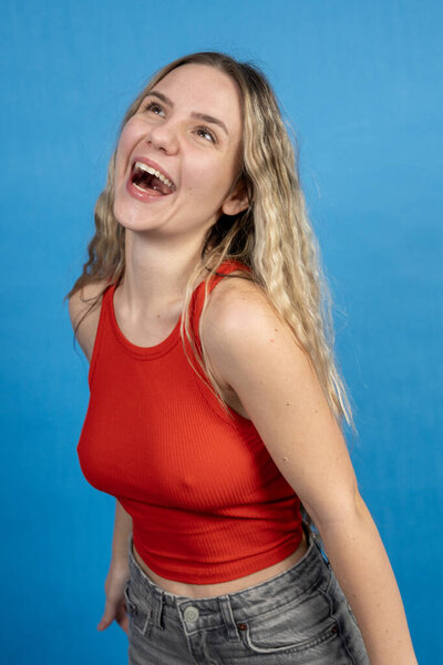 Happy woman laughing against a bright blue background