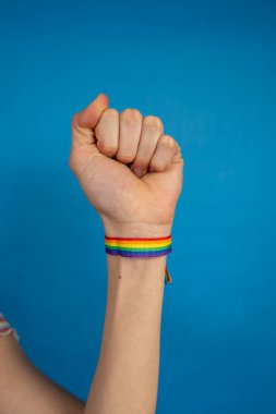 Yumruk hareketi yapan gökkuşağı bilekliğiyle el, lgbtq + topluluğunun gururunu sembolize ediyor ve eşit haklar için savaşıyor.