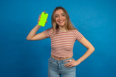 Gülümseyen kadın yeşil renkli ekranlı akıllı telefonu gösteriyor. Reklam ve uygulama promosyonu için ideal.