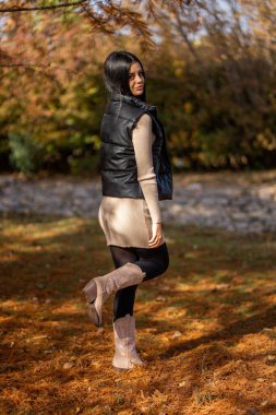 Şık bir model, sakin bir orman ortamında sonbahar moda eğilimlerini sergiliyor