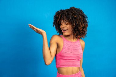 Avucunun içinde mavi arka planda bir şey gösteren gülümseyen kadın.