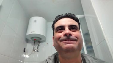 Adam yüzünü banyoda sabunla yıkıyor.