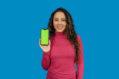 Gülümseyen kadın yeşil ekranlı akıllı telefonu gösteriyor. Uygulamaları veya web sitelerini göstermek için mükemmel.