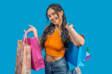 Mağazadaki ürünleri satın aldıktan sonra renkli alışveriş torbalarını gösteren mutlu müşteri mevsimlik satışlardan ve indirimlerden keyif alıyor.