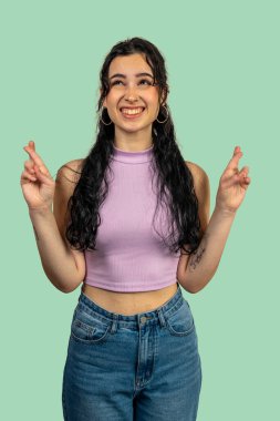 İyimser genç bayan yeşil arka planda bir gülümsemeyle şans diliyor.