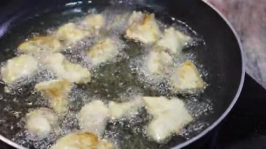 Tavada kızgın yağda kızarmış tavuk eti, çatalla karıştırılmış.