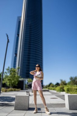 İspanya 'nın Madrid kentindeki Cuatro Torres İş Bölgesi' nde yaz güneşli bir günde elinde tablet ve poz tutan iş kadını