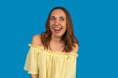 Neşeli genç bir kadının neşeli bir ifadeyle dilini dışarı çıkaran stüdyo portresi.